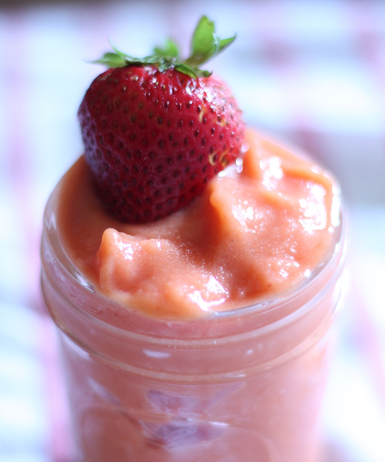 strawberry mango smoothie in small mason jar with strawberry on top