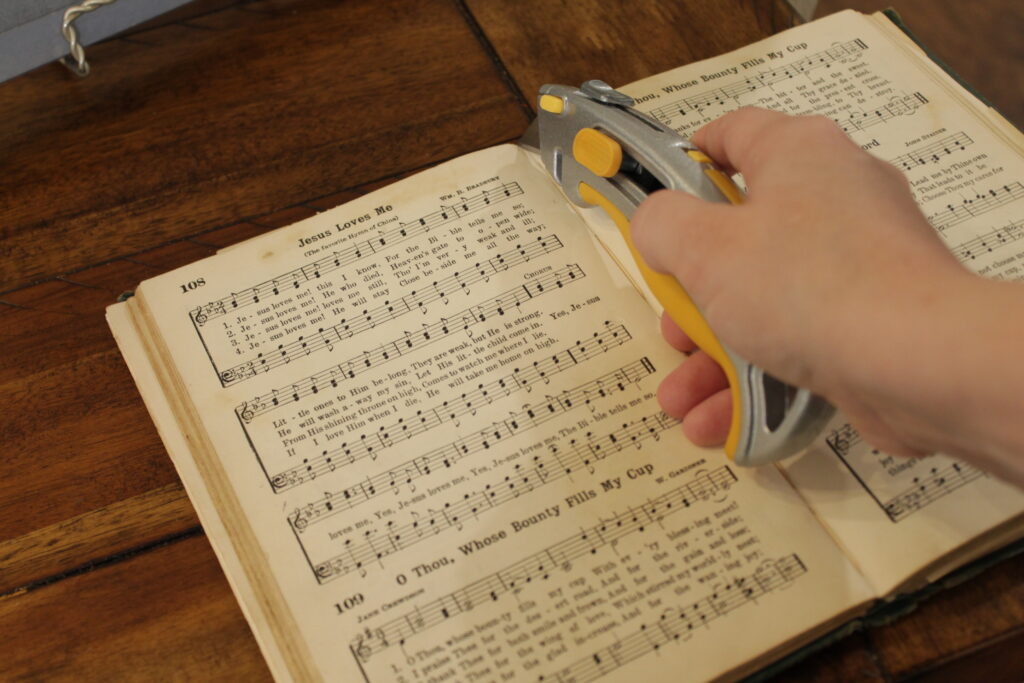 box cutter cutting page out of hymn book