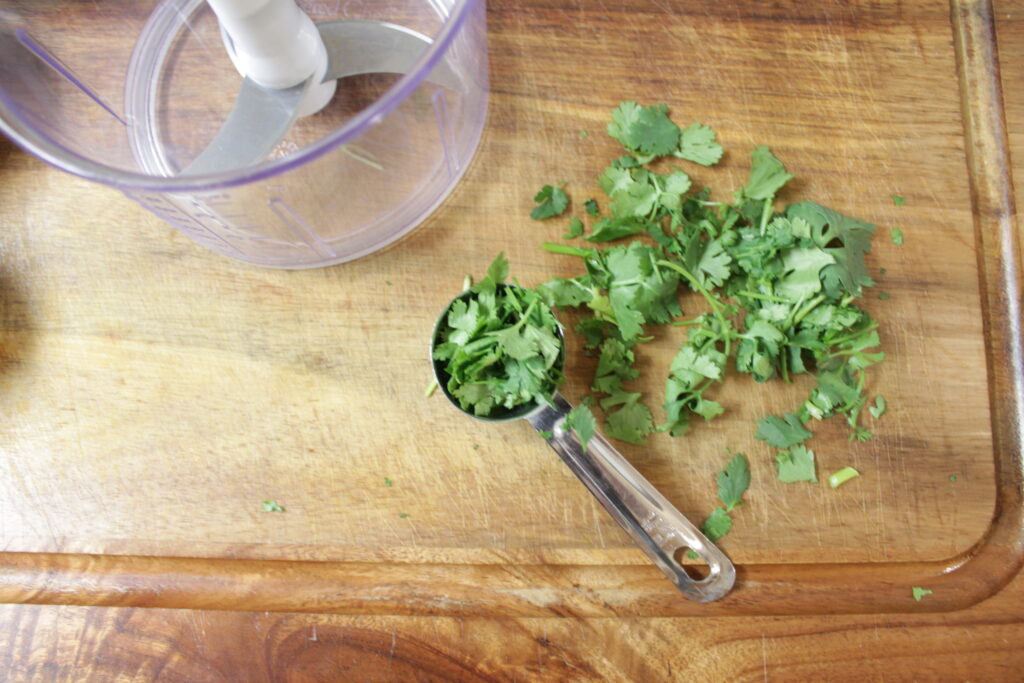 tablespoon full of cilantro laying on cutting board 