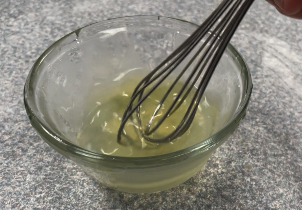 whisking egg whites with water in small glass bowl 