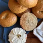 potato flake sourdough bagels on cutting board, one sliced open, spread with cream cheese
