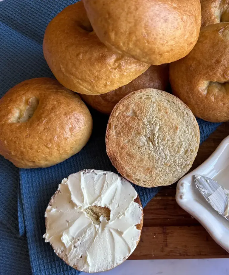 potato flake sourdough bagels on cutting board, one sliced open, spread with cream cheese