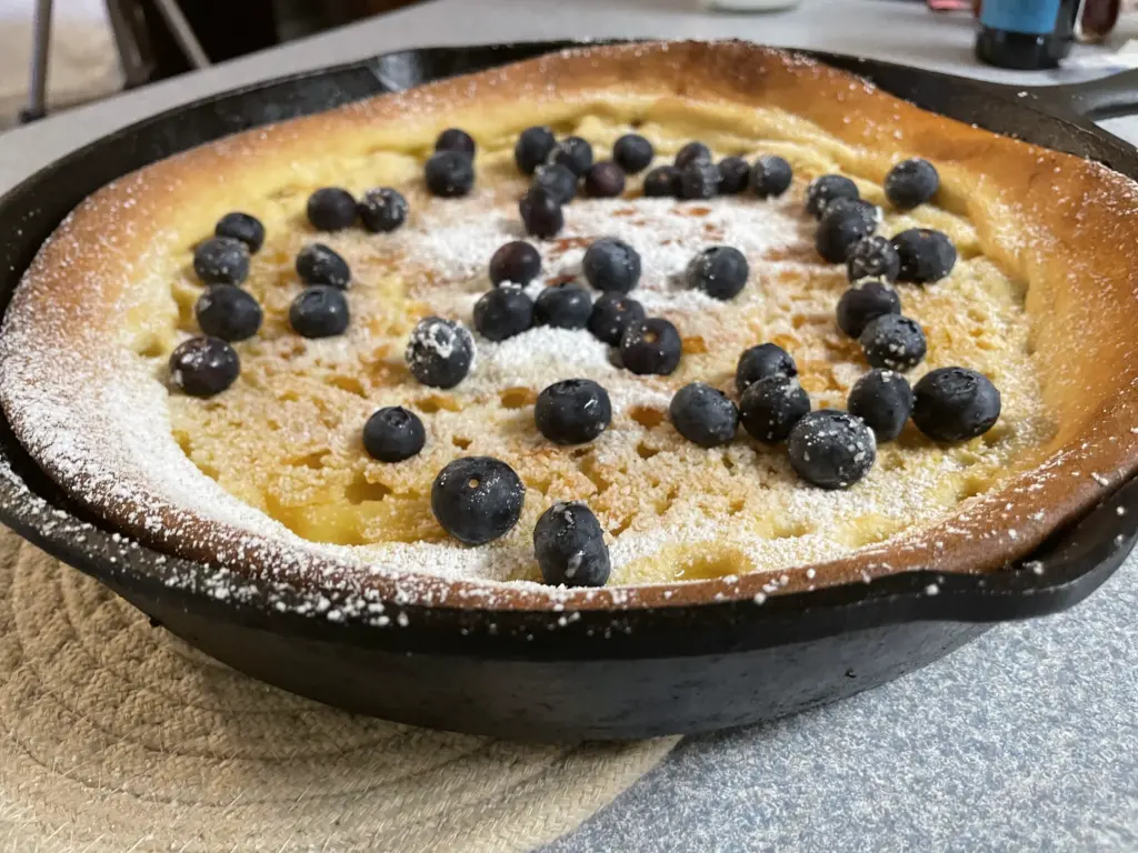finished dutch baby with blueberries and powdered sugar
