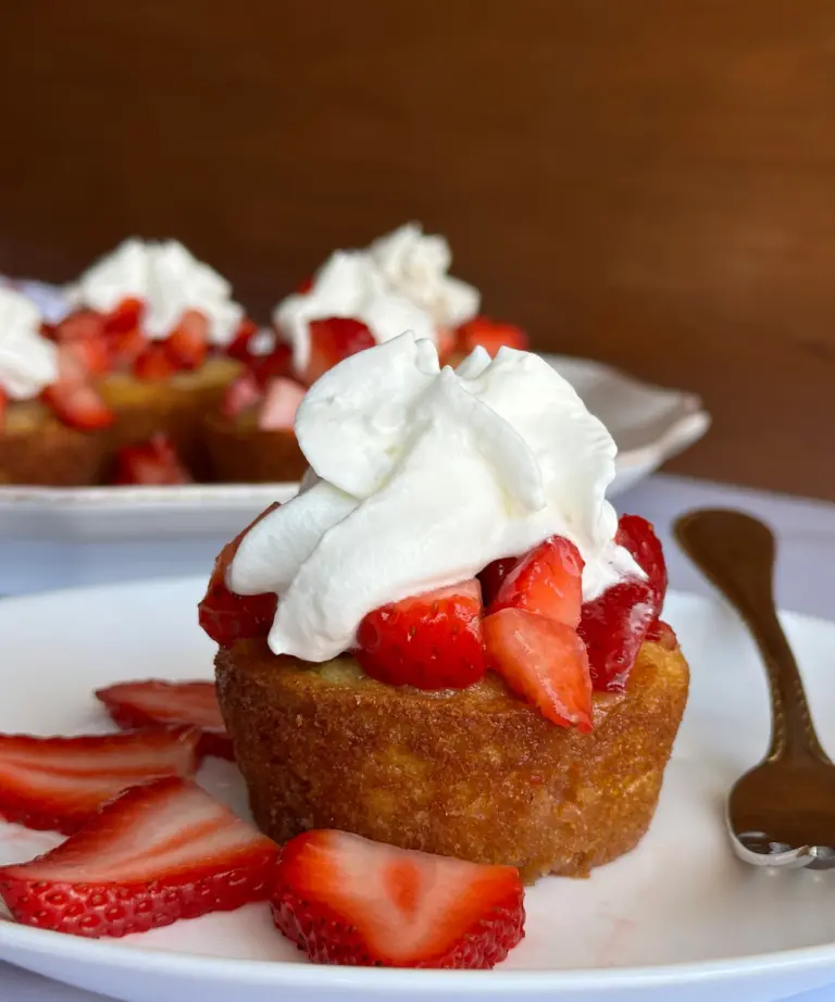 sourdough strawberry shortcake topped with strawberries and whipped topping on a white plate
