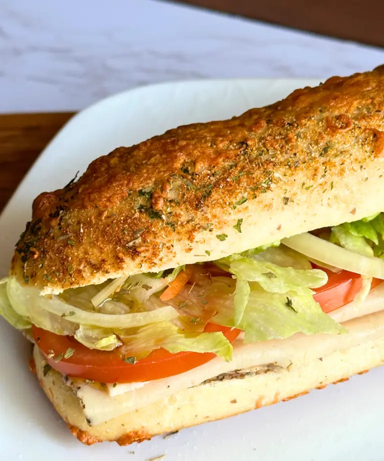 potato flake sourdough Italian herb and cheese bread on a white plate used for a cold sandwich