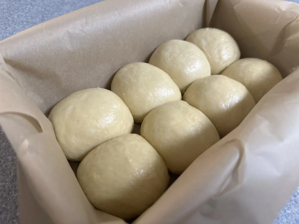 potato flake sourdough brioche dough balls in loaf pan before final rise